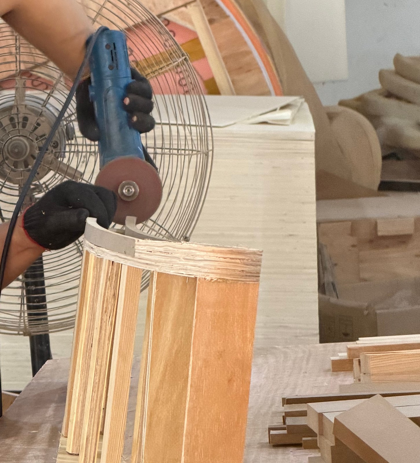 Hands working on the edge of a wood furniture frame at the Lenatees factory