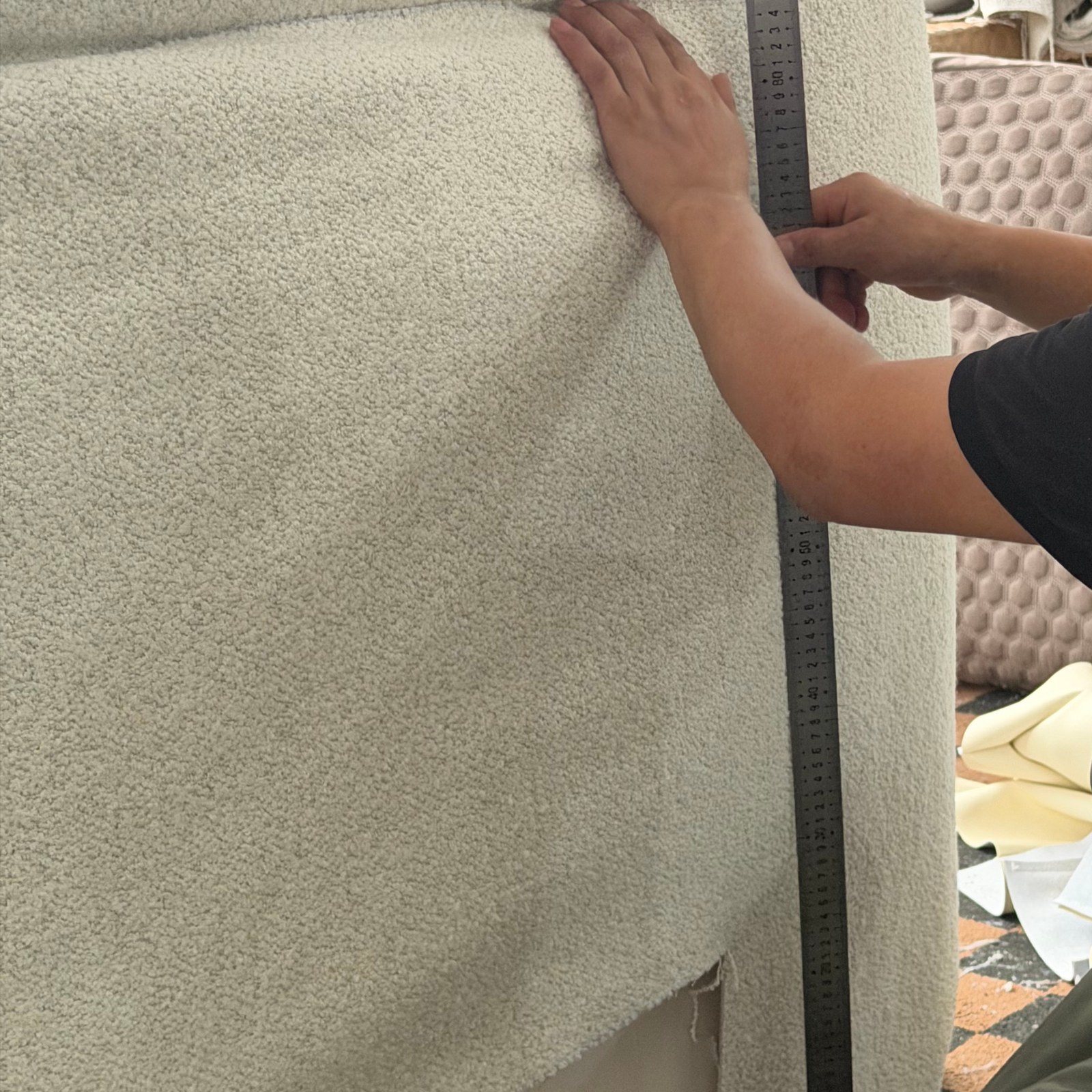 A worker checking dimensions on an upholstered furniture component