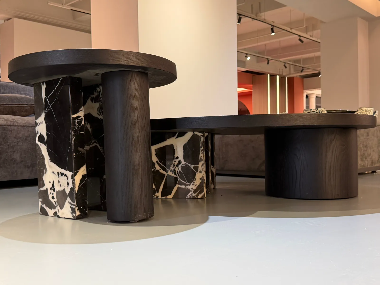 Rounded tables with dark wood surfaces and black-and-white stone-pattern supports in a furniture display area