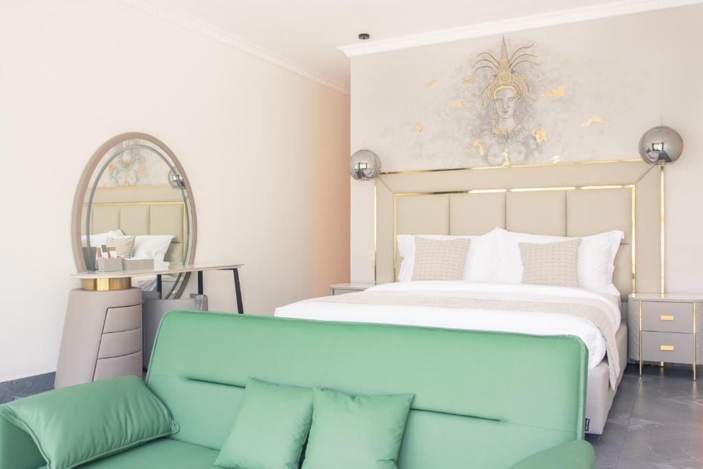 Hotel guestroom with upholstered bed, nightstands, dresser, mirror and sofa