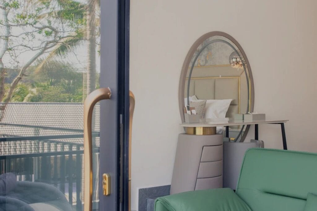 Hotel guestroom dresser and oval mirror beside an upholstered sofa