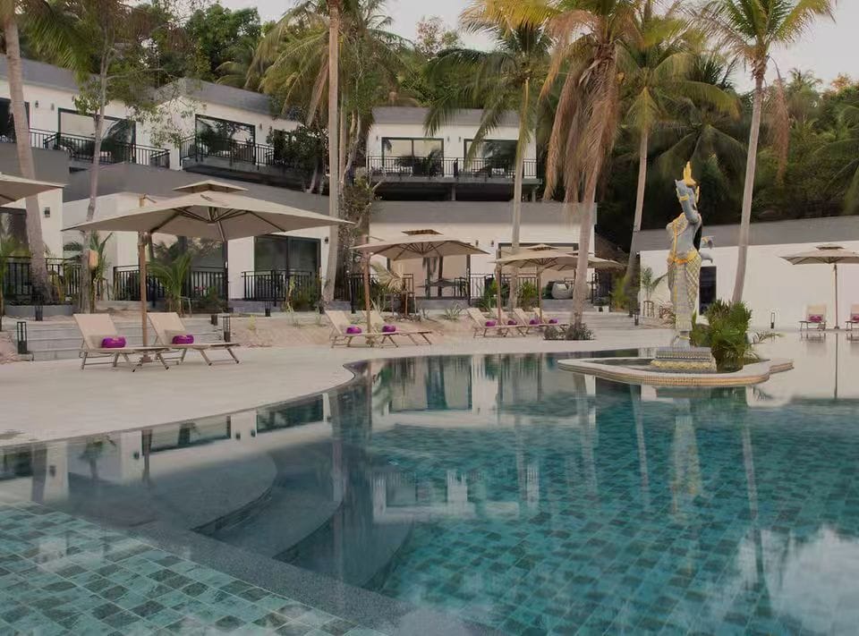 Resort pool area surrounded by guestrooms and outdoor furniture