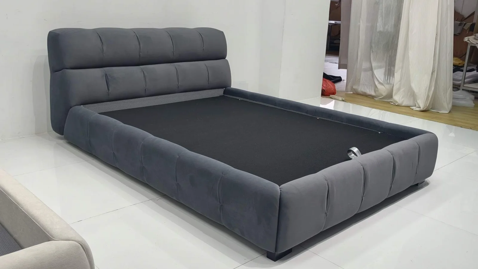 Grey upholstered bed with padded headboard, side rails and footboard